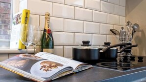 A kitchen with white tiled backsplash, a book, a bottle of champagne, and a pot on the stove. - Ideal for Contractors | Free Wi-Fi | Sleeps 7! (Northampton)