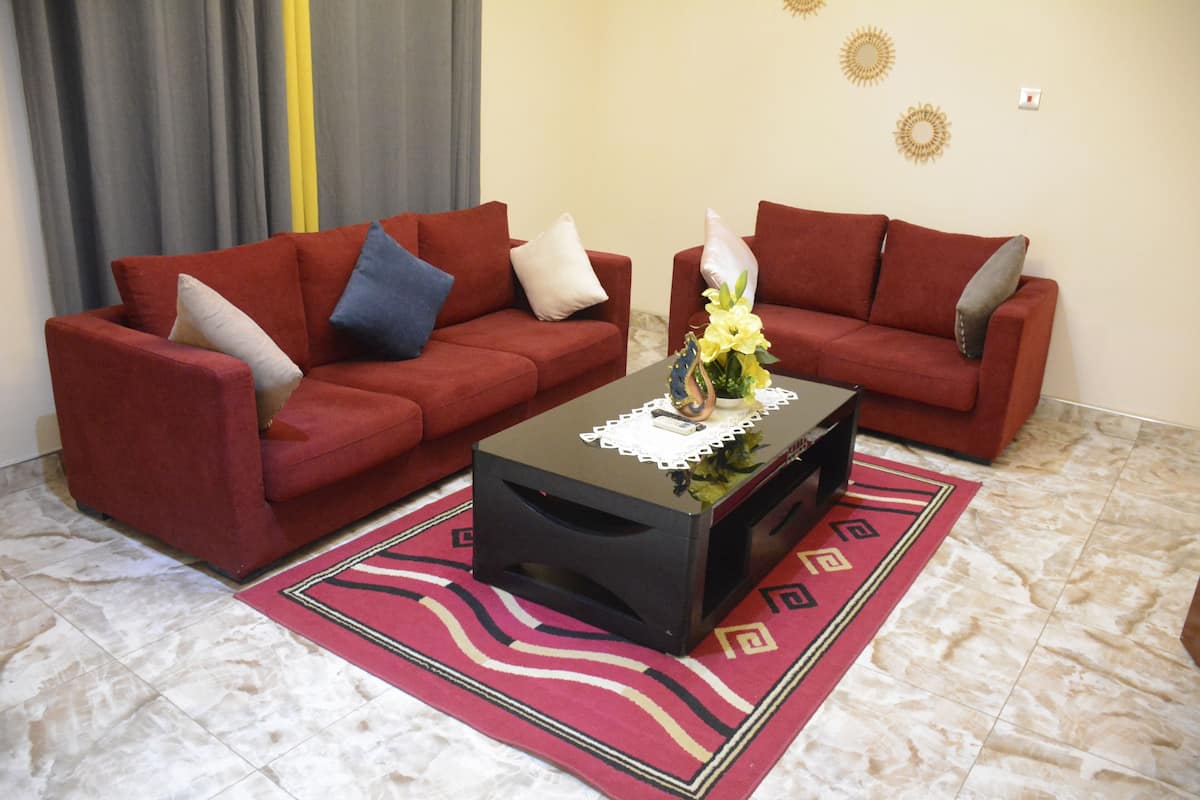A living room with two red sofas, a black coffee table, and a red patterned rug.