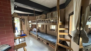 A dormitory room with bunk beds, a wooden ladder, a small table with a chair, and a window with curtains. - OYO 1173 Sermon On The Mount Retreat (Balamban)