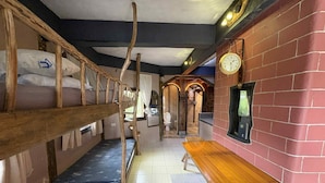 A room with bunk beds, a wooden table, and a brick wall with a clock. - OYO 1173 Sermon On The Mount Retreat (Balamban)