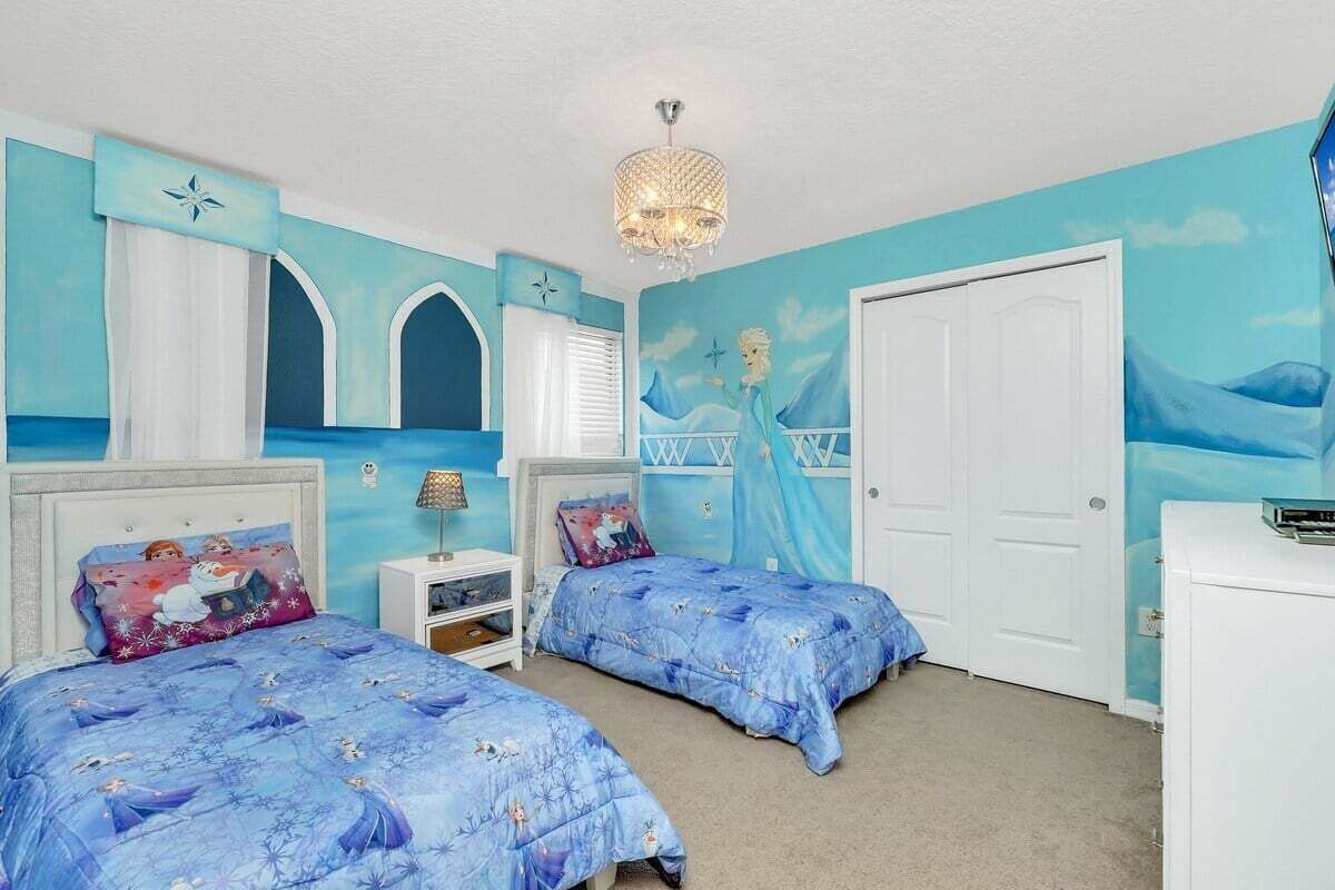 Un dormitorio con dos camas, una araña y un mural en la pared.