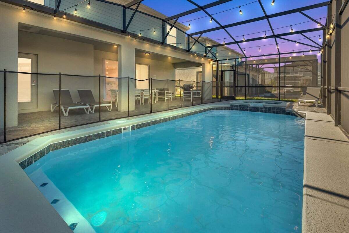 An indoor swimming pool with a glass ceiling, lounge chairs, and a seating area.
