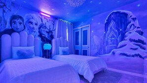 A bedroom with two beds, a large mural on the wall, and a door leading to another room.