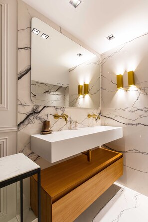 A bathroom with a white marble sink, gold fixtures, and a wooden vanity. - Charming Apart - 3br/6p - Jardin du Luxembourg (Paris)