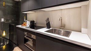 A modern kitchen with black cabinets, a white countertop, a stainless steel sink, and a built-in oven. - Cosy Apart - 3br/6p - Jardin du Luxembourg/odeon (Paris)