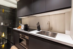 A modern kitchen with black cabinets, a white countertop, a stainless steel sink, and a built-in oven. - Charming Apart - 3br/6p - Jardin du Luxembourg (Paris)