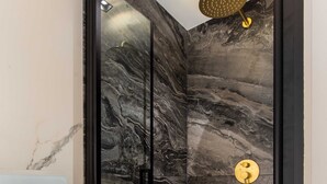 A modern bathroom with a glass-enclosed shower, marble walls, and a gold showerhead. - Cosy Apart - 3br/6p - Jardin du Luxembourg/odeon (Paris)