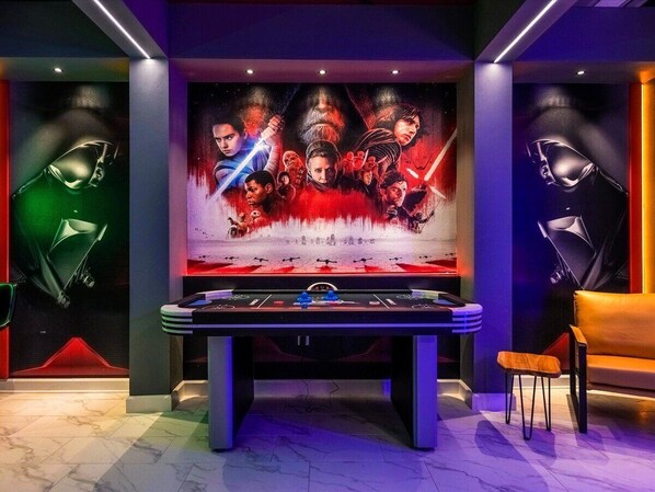 A foosball table in a room with a Star Wars-themed mural on the wall.