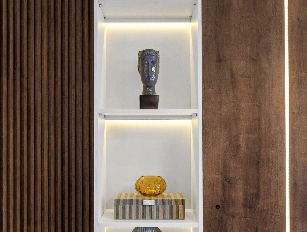 A shelf with a bust sculpture and a yellow vase on a striped box.