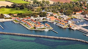 A coastal marina with docked boats, a marina building, and surrounding residential areas with houses and greenery. - Holiday Home on the Harbour in Borre (Borre)