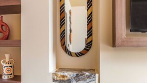 A bathroom with a mirror, a shelf with decorative items, a blue bench, and a marble countertop. - Gorgeous Apartment - 2br/8p - Le Marais (Paris)