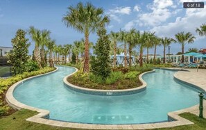 Piscina com design curvo, cercada por palmeiras e vegetação.
