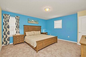 Quarto com cama de madeira, mesa de cabeceira, cômoda e um quadro na parede.