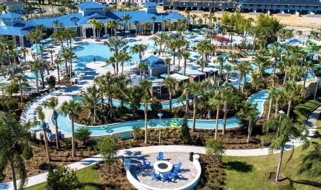 A resort with multiple swimming pools, palm trees, and a large water slide.
