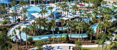 A resort with multiple swimming pools, palm trees, and a large water slide.