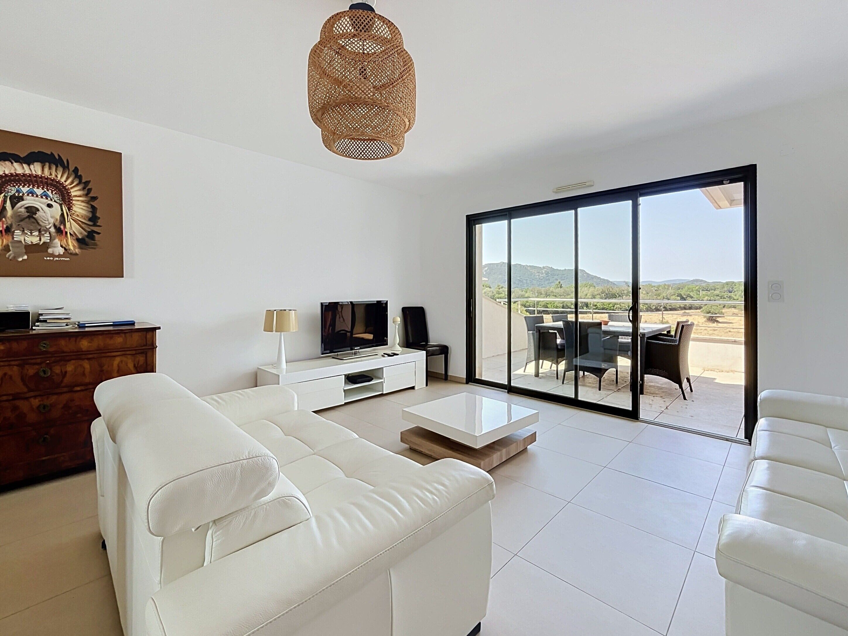 A modern living room with a sofa, TV, and a dining area with chairs and a table.