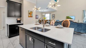 Una cocina moderna con una isla central, armarios negros y electrodomésticos de acero inoxidable.