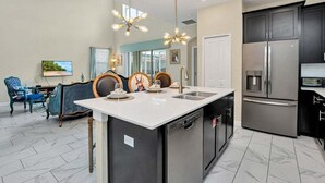 Una cocina moderna con una isla central, electrodomésticos de acero inoxidable y un comedor con sillas azules.