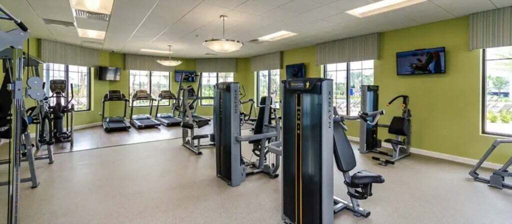Une salle de sport équipée de tapis de course, d’appareils de musculation et d’autres équipements d’exercice.