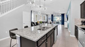 A modern kitchen with a central island, dark cabinetry, and stainless steel appliances. - Last Minute Disney! Private Pool, Hot Tub, Game Room & Themed Bedrooms. Book Now! #WIR405 (Orlando)