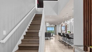 A modern kitchen with a central island, bar stools, and pendant lighting.