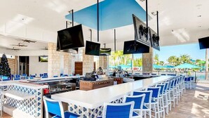 A bar area with multiple seating arrangements, a counter, and overhead televisions.