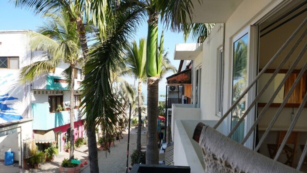Een balkon met uitzicht op een straat met palmbomen en gebouwen.