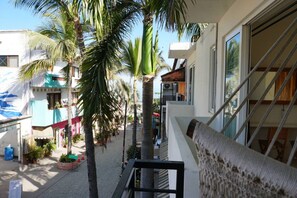 Un balcón con vista a una calle bordeada de palmeras y edificios.
