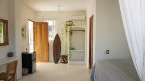Een slaapkamer met een bed, een bureau en een surfplank.