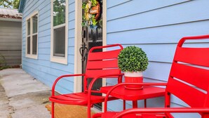 A red metal chair with a small potted plant on a blue house exterior.