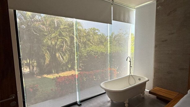 Une salle de bain moderne avec une baignoire îlot, de grandes portes coulissantes en verre donnant sur un jardin et un design minimaliste.