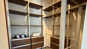 Un dressing avec de nombreuses étagères et tiroirs en bois, une porte blanche et un luminaire au plafond.