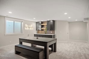 Une cuisine moderne avec des meubles de couleur sombre, un îlot central intégré et un néon mural.