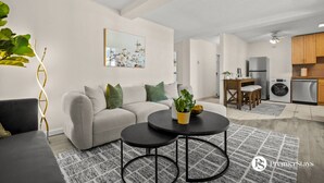 Un salon moderne avec un canapé, une table basse et un tableau accroché au mur.