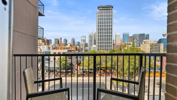 Un balcon offrant une vue sur le paysage urbain, avec notamment un immeuble de grande hauteur et divers autres bâtiments.