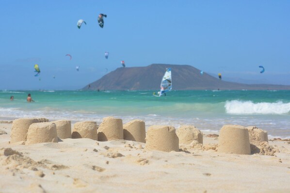 Une plage avec des sculptures de sable et une vue dégagée sur l’océan.