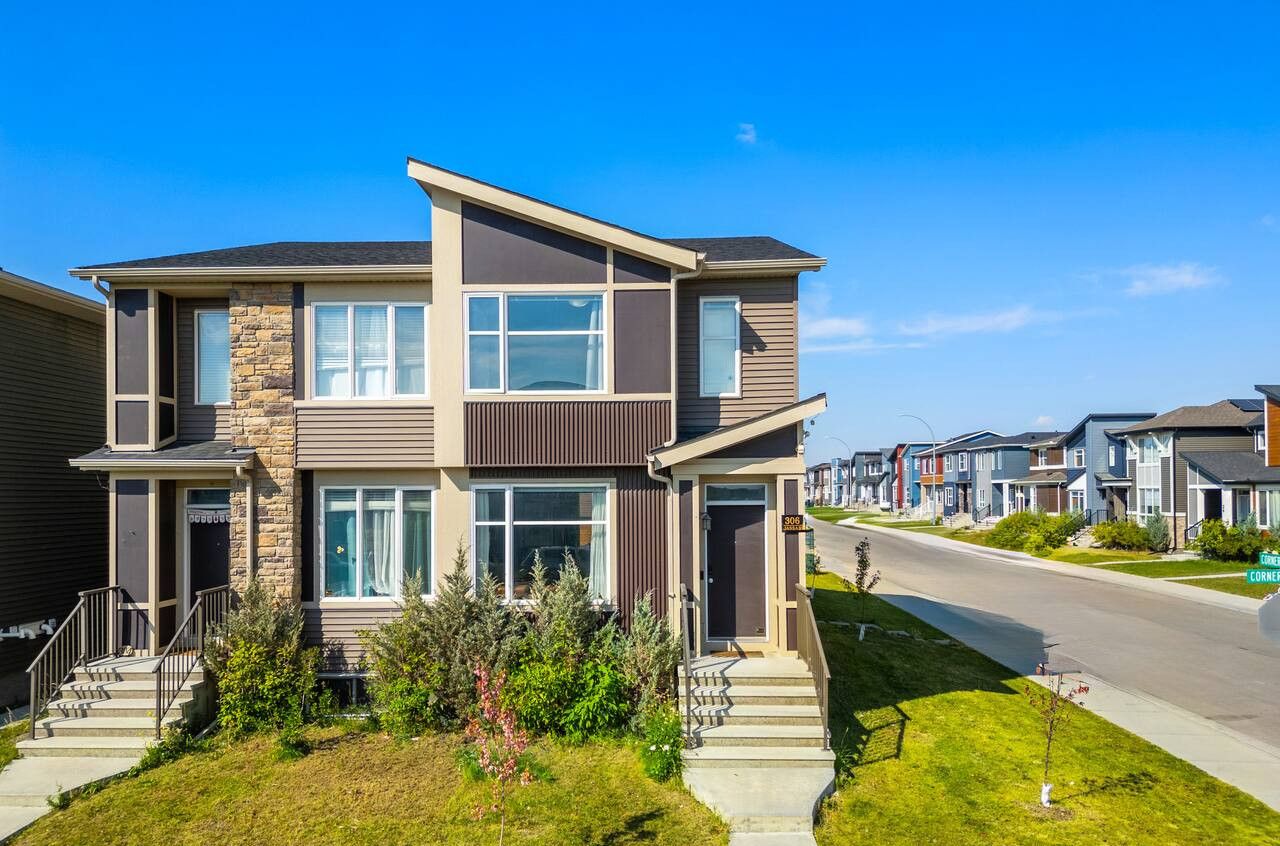 A modern two-story house with a stone facade, large windows, and a well-maintained lawn.
