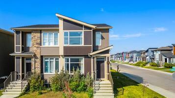 A modern two-story house with a stone facade, large windows, and a well-maintained lawn.