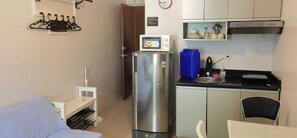 Eine kleine Küche mit Kühlschrank, Mikrowelle und Spüle.