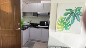 Una cocina con armarios blancos, un microondas y un escurreplatos verde.
