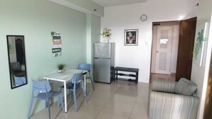 Un espacio habitable compacto con comedor, refrigerador, una pequeña banca y un sofá.
