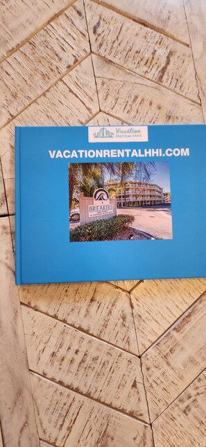 Un petit livret bleu avec une photo d’un bâtiment portant l’inscription « Breakers » et le texte « VacationRentalHHI.com ».