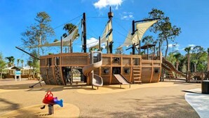 A wooden play structure resembling a pirate ship with slides and climbing areas.