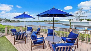 A deck with outdoor furniture and umbrellas overlooking a body of water. - 4-bedroom 3 bathroom room house with AC with Private Pool in great Pompano Beach (Pompano Beach)