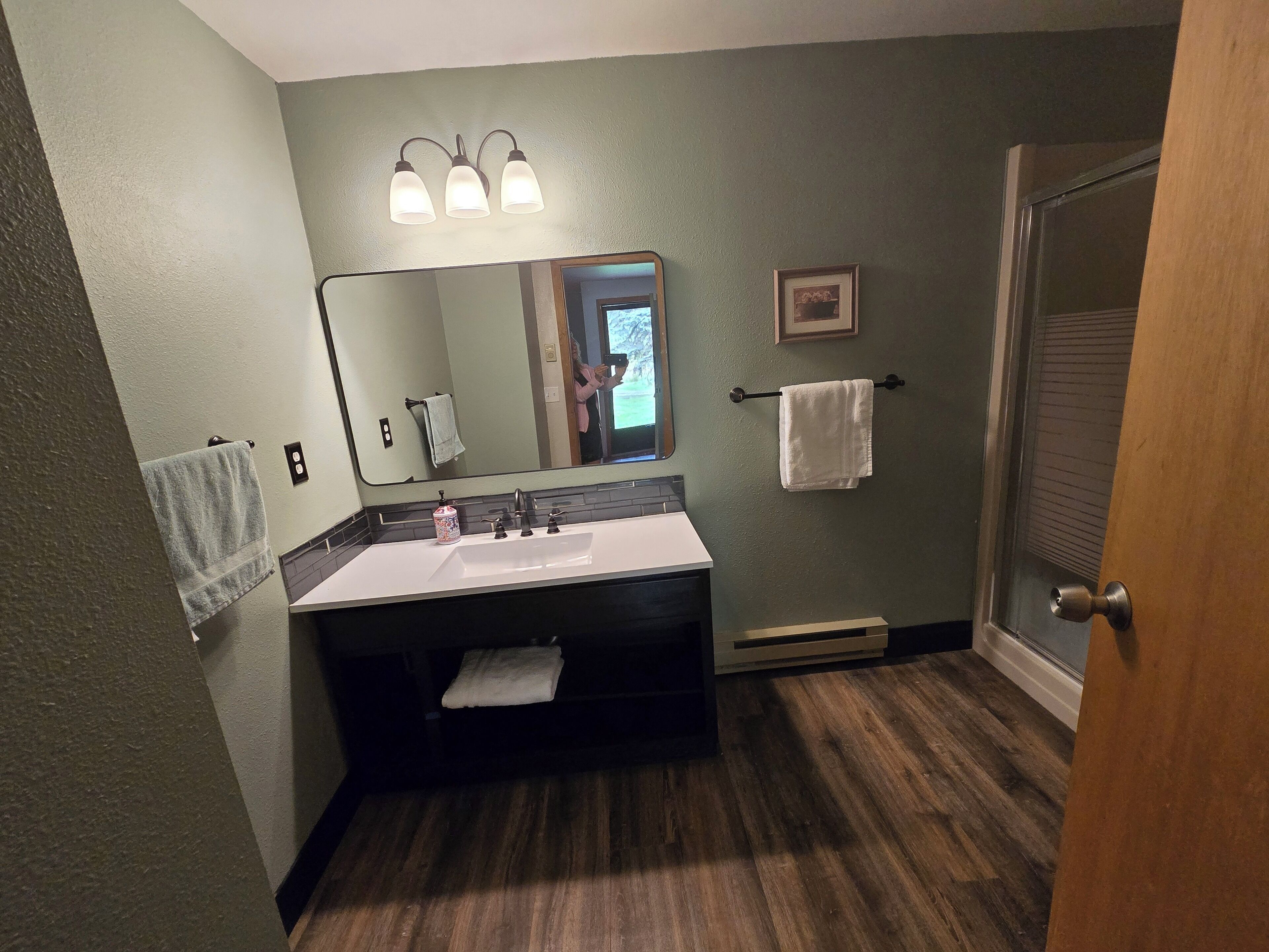 Un baño con lavabo, espejo, toallero y una puerta.