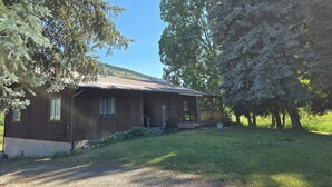 A rustic cabin with a metal roof, surrounded by trees and a grassy yard. - Country Living 6 miles from Colville, easy access, on a beautiful large pond! (Colville)