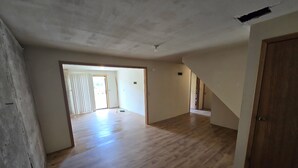 An open-plan living area with wooden flooring, a large door, and a view to a balcony. - Country Living 6 miles from Colville, easy access, on a beautiful large pond! (Colville)