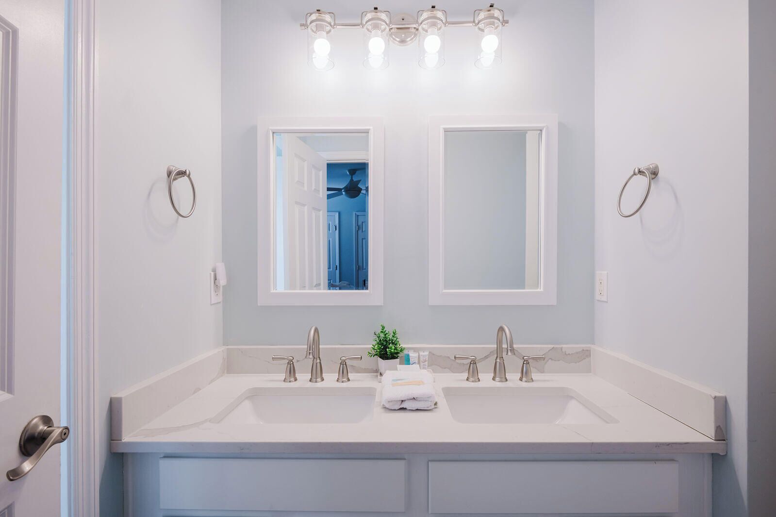 Une salle de bain avec deux lavabos, un miroir et un luminaire au-dessus.