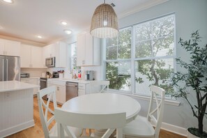 Una cocina moderna con armarios blancos, una mesa redonda y una lámpara colgante.