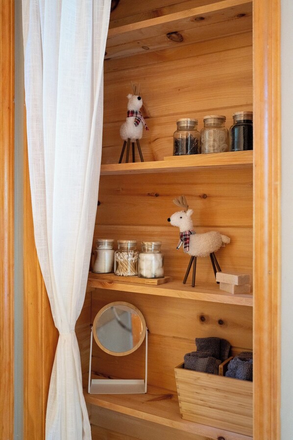 Une étagère en bois avec des bocaux, un miroir et deux peluches en forme de renne.